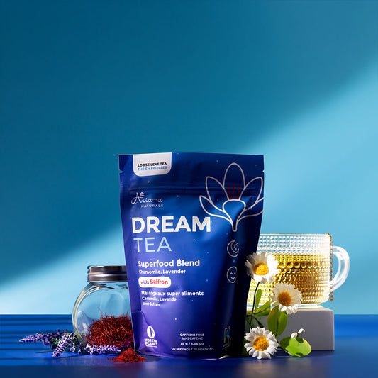 Ariana Naturals Dream Tea pouch with a cup of tea and it's ingredients, a jar of saffron, chamomile flowers, and lavender on a multi blue background