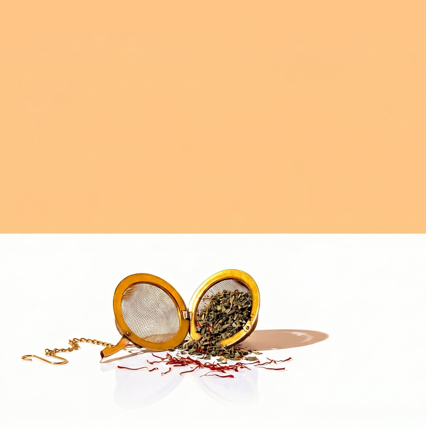 Tea infuser with loose tea on a white surface with a peach-colored background